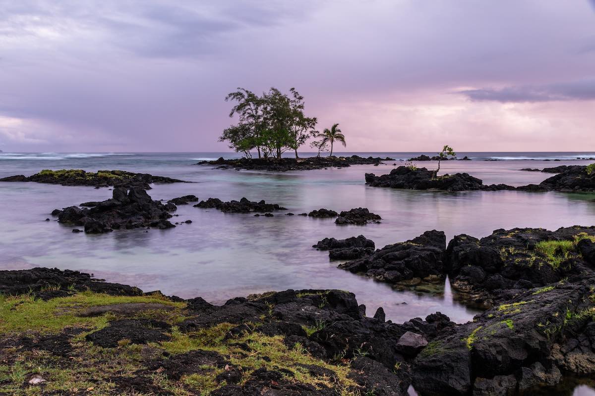 Check out this list of the best beaches in Hilo Hawaii recommended by top Hawaii blog Hawaii Travel with Kids. Image of a rocky beach with a purple sky