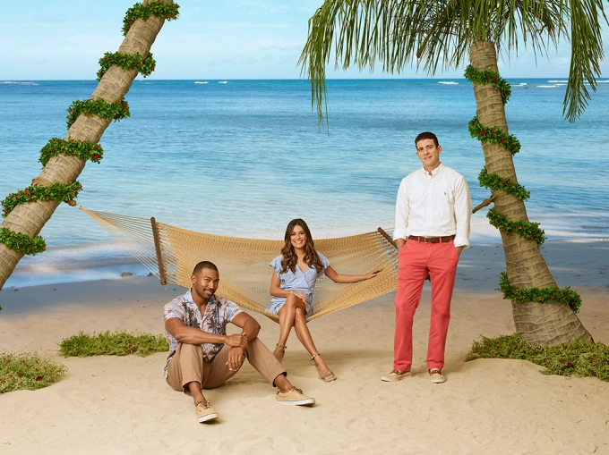 Image of a woman and two men posing with a hammock and palm trees