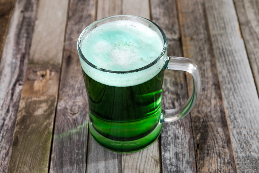 Celebrating St. Patrick's Day on Maui. Single mug of green beer on wooden background. Tabletop, side view.