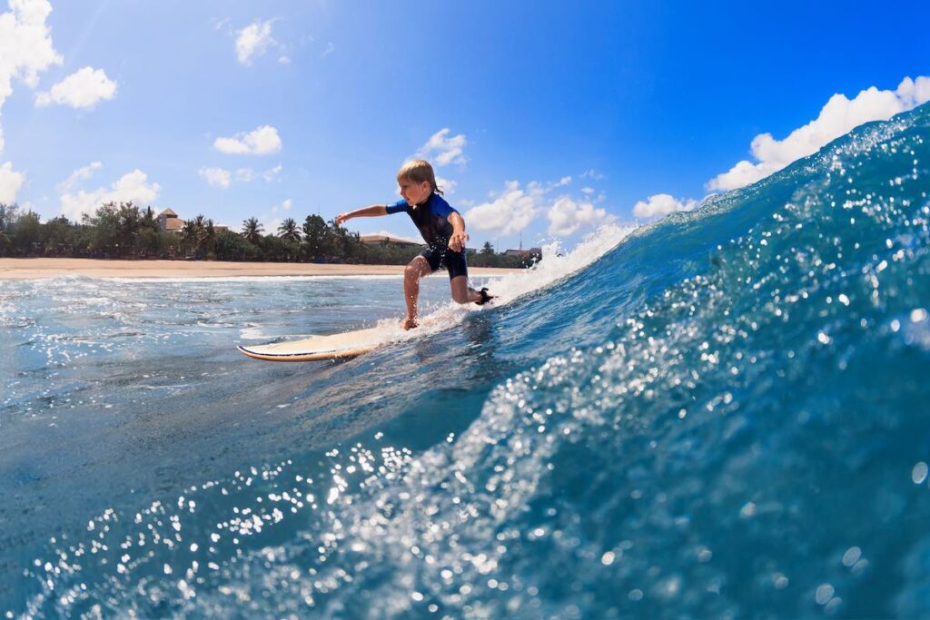 Find out the best things to do in Maui in February recommended by top Hawaii blog Hawaii Travel with Kids. Image of a boy surfing in the ocean.