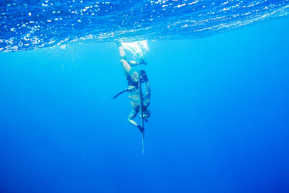 Underwater hunter  with gun dives into the depths of the sea