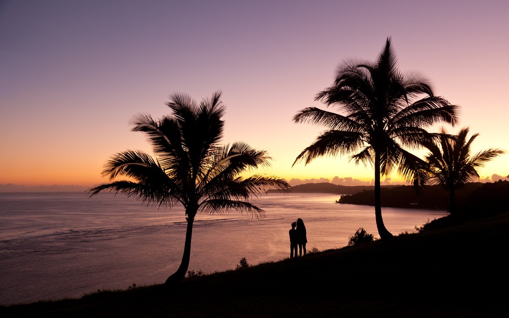Sunrise with couple between two palm trees and looking towards Kilauea lighthouse