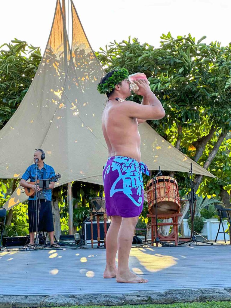 Image of a man blowing a conch shell at a Kona luau