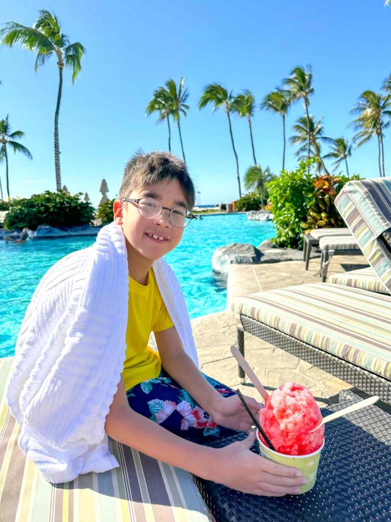Image of a boy holding a red shave ice by the pool at the Fairmont Orchid in Kona Hawaii