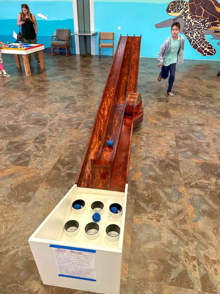 Image of a boy rolling a ball down a wooden ramp at the Hawaii Keiki Museum.