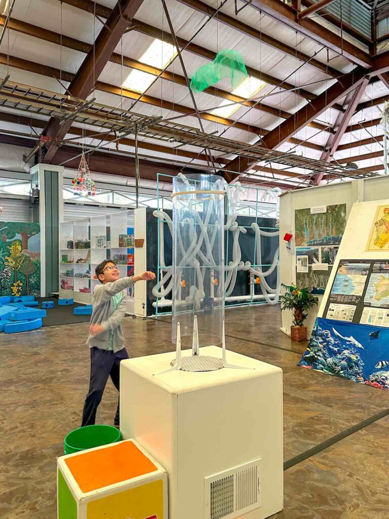 Image of a boy dancing after his scarf shoots out of a wind tunnel