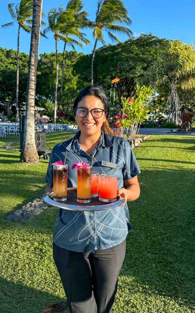 Image of a server offering tropical drinks at the Hawaii Loa Luau in Waikoloa