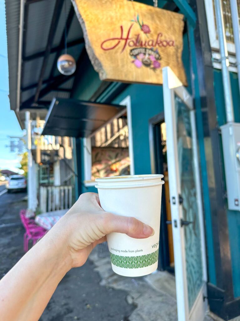 Image of a coffee cup in front of the Holuakoa Coffee Shack sign