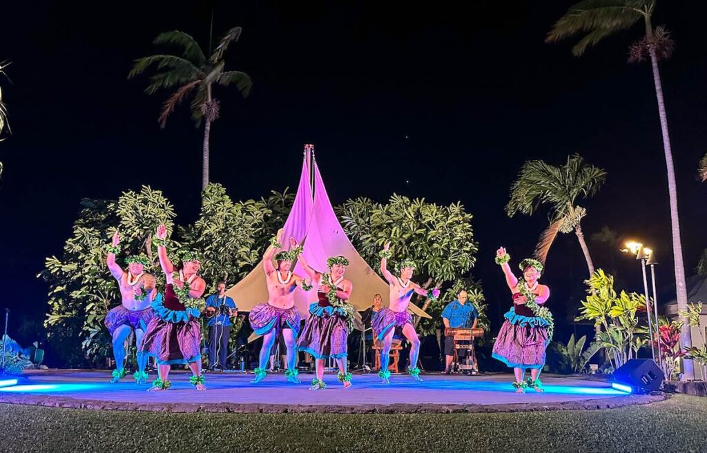 Image of hula dancers wearing purple costumes at a luau in Hawaii