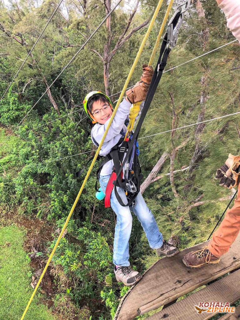 Image of a boy rappelling off a ziplining platform