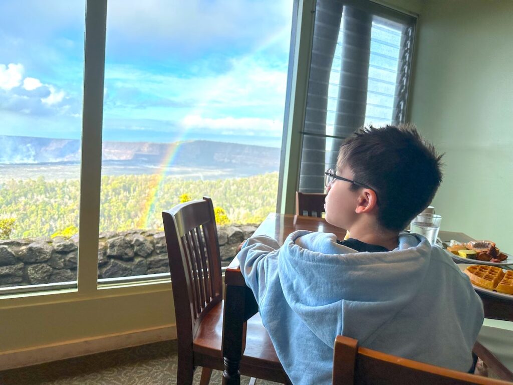Image of a boy having breakfast while looking at a rainbow