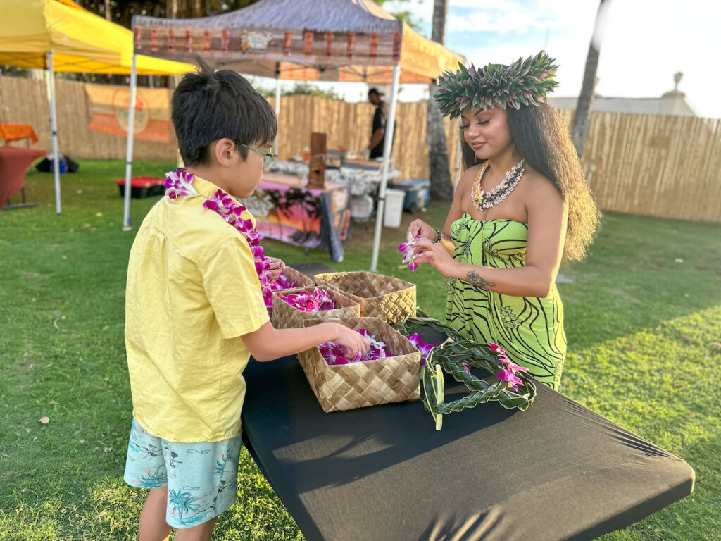 Image of a boy learning how to make a lei at Diamond Head Luau on Oahu. Photo credit: Marcie Cheung of Hawaii Travel with Kids