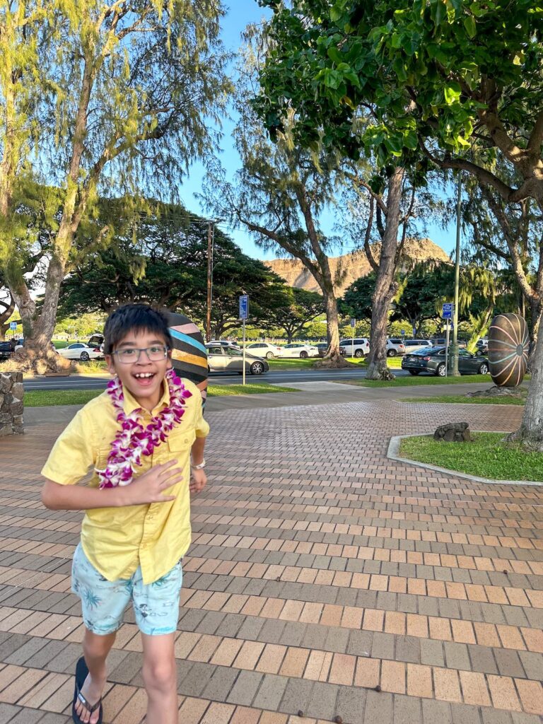 Image of a boy wearing a lei running around Waikiki Aquarium. Photo credit: Marcie Cheung