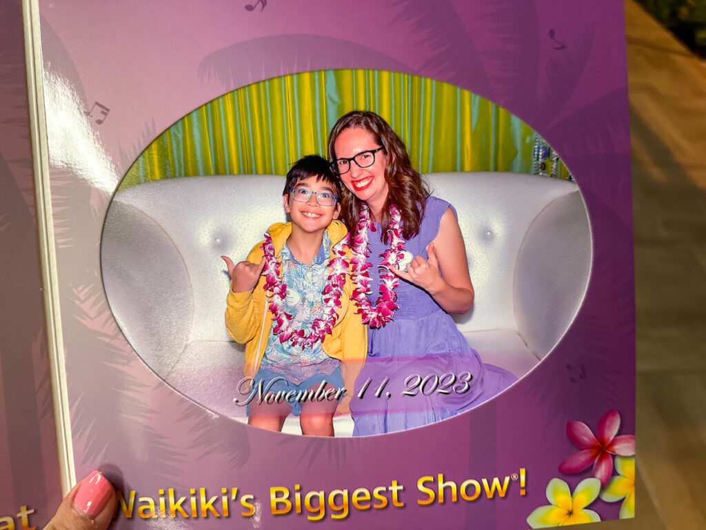 Image of Marcie Cheung of Hawaii Travel with Kids and her son in a souvenir photo at the Rock a Hula luau in Waikiki.