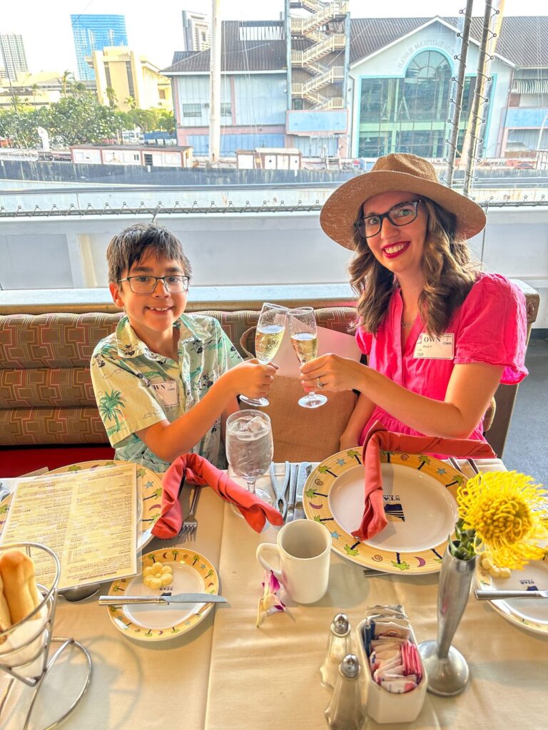 Image of Marcie Cheung of Hawaii Travel with Kids and her son with champagne on the Star of Honolulu dinner cruise in Hawaii.