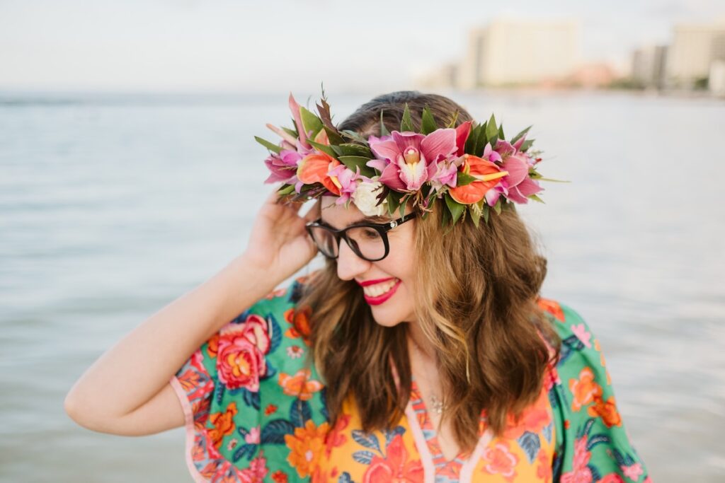 Image of Marcie Cheung of Hawaii Travel with Kids wearing a lei po'o (flower crown) at Waikiki Beach during a photo session