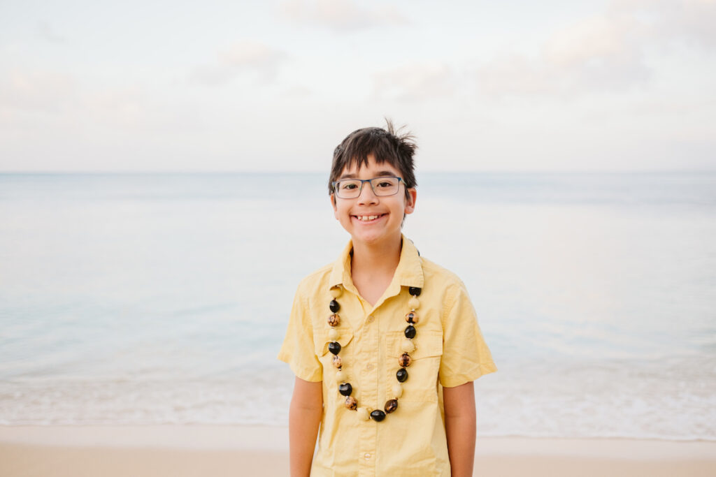 Image of a boy wearing a kukui nut lei and a yellow shirt for a photo shoot in Waikiki