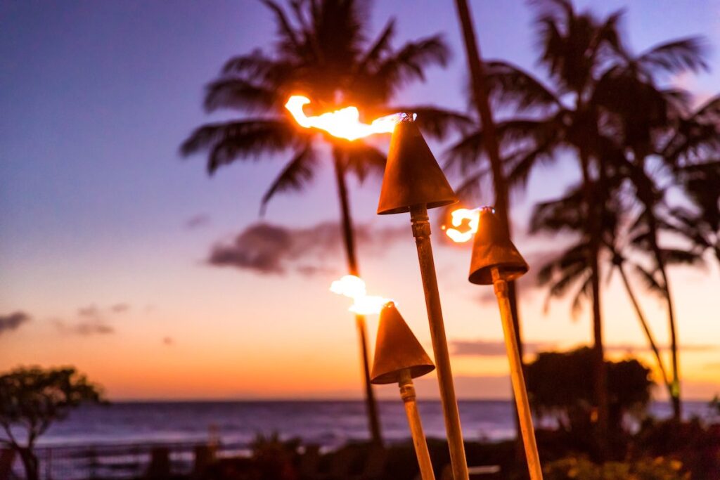 Hawaii sunset with fire torches. Hawaiian icon, lights burning at dusk at beach resort or restaurants for outdoor lighting and decoration, cozy atmosphere.