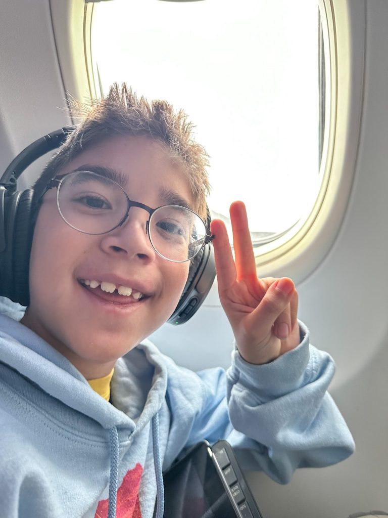 Image of a boy throwing a peace sign in an airplane