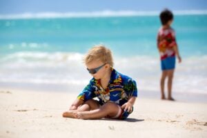 Image of Happy beautiful fashion family, mom and children, dressed in hawaiian shirts, playing together on the beach, famiy joyful vacation
