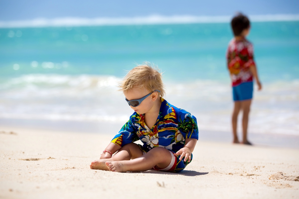 Image of Happy beautiful fashion family, mom and children, dressed in hawaiian shirts, playing together on the beach, famiy joyful vacation