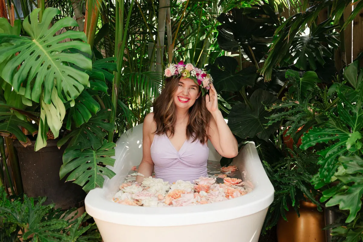 Image of Marcie Cheung, certified Hawaii Destination Expert in an outdoor bath tub full of flowers