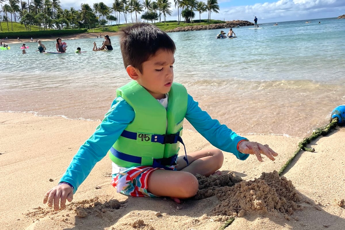 Image of a boy at a Ko Olina lagoon playing in the sand