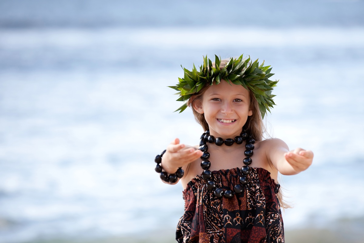 Image of a girl dancing hula in front of the ocean