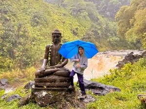 Image of a boy holding an umbrella next to a statue in Hilo on the Big Island